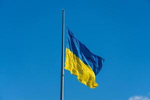 The vibrant blue and yellow colors of the Ukrainian flag flutter against a pristine blue sky photo