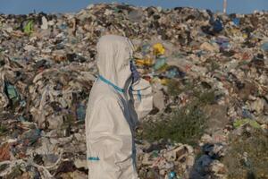 Workers in protective gear examine extensive piles of waste at a garbage dump, highlighting the urgent issues of pollution and the need for effective waste management practices photo