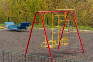 Brightly colored swings stand in an empty playground, surrounded by lush greenery. This inviting setting encourages children to engage in active play and create joyful memories outdoors photo