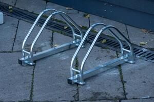 Sturdy and modern bicycle parking rack made of metal stands on a paved sidewalk, ready to support bikes for riders in a bustling urban environment photo