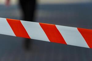 Brightly colored caution tape is prominently displayed against a blurred urban background, marking an area of restriction for public safety during ongoing construction work photo