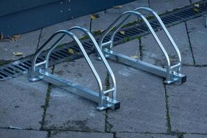 Well-designed bicycle racks stand ready for riders in a bustling neighborhood. The metallic structure gleams under sunlight, inviting cyclists to securely park and thrive photo