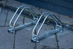 Two sleek metal bicycle racks stand on a paved surface, ready to provide secure parking for bicycles. The sleek design adds a modern touch to the urban environment photo