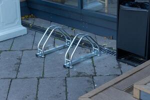 A modern bike rack is placed on a sleek pavement beside a building, surrounded by a tidy urban environment, showcasing practicality and design photo