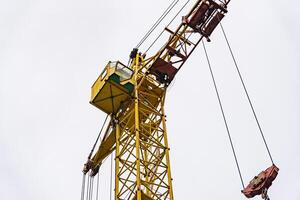 The bright yellow crane dominates the skyline, its operator carefully maneuvering materials for an ongoing construction project as clouds roll by above photo