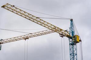 Tall construction cranes reach for the sky, their yellow and blue structures stark against the overcast backdrop, highlighting a city in development photo