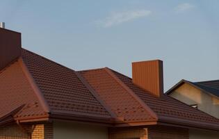 The image showcases a stylish house featuring a modern metal tile roof, designed to enhance the architecture. Sunlight reflects off the roof, highlighting its unique texture photo