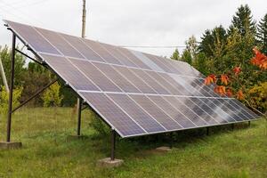 Solar panels are strategically positioned on a metal frame, capturing sunlight in a green field while surrounded by trees and foliage on a cloudy day photo