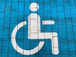 A bright blue pavement features a clear white symbol indicating accessible parking for individuals with disabilities, emphasizing inclusivity and safety photo