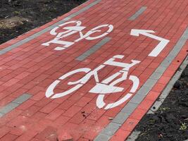 A freshly marked bicycle lane features large symbols for cyclists, guiding bikers along a red brick pathway designed for safer riding in the city photo