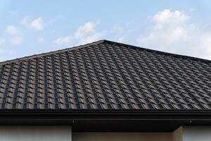 The rooftop features precisely laid roof tiles, showcasing a careful and skilled application. Bright sunlight emphasizes the textured pattern on the tiles, creating an appealing aesthetic photo
