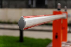 A barrier gate stands closed, regulating access to a controlled area in a city environment. The bright colors highlight its purpose for security and management photo