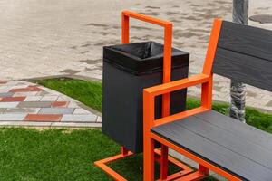 A stylish garbage container is integrated with a bench in a green park area, encouraging visitors to dispose of trash responsibly while enjoying the outdoors photo