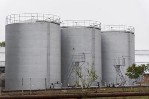 Three large, cylindrical grain storage silos stand tall, contributing to efficient harvest management on a modern agricultural farm. Automated systems assist in grain handling photo