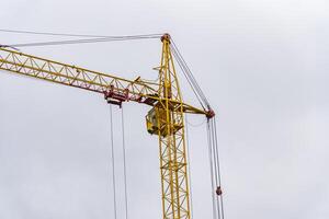A large yellow crane lifts construction materials at a busy site under a cloudy sky, showcasing its essential role in heavy machinery operations and building projects photo