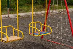 The vibrant yellow swings sway gently in the breeze, encouraging children to engage in outdoor play. Nearby, a safe surface and ample space enhance the joyful atmosphere photo