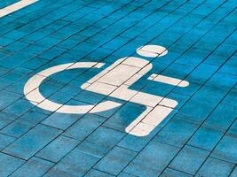 A designated parking spot reserved for disabled individuals features a bright blue paving and a clear accessibility symbol painted in white. This ensures easy identification and access photo