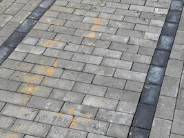A gray brick pavement with black stripes. There is some dirt and debris on the bricks photo