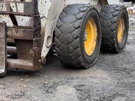 A bobcat tractor equipped with heavy tires is actively maneuvering through uneven ground at a construction site, showcasing its power and utility photo