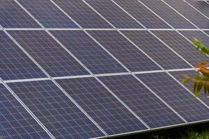 A series of solar panels capture sunlight in a systematic arrangement, contributing to renewable energy production in an urban setting during broad daylight photo