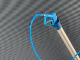 A high-pressure car washer gun with a sturdy nozzle and flexible hose is positioned upright, designed for efficient cleaning of vehicles outdoors photo