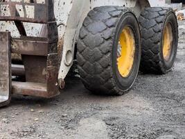 The compact loader is positioned on a gravel surface, showcasing its robust tires designed for traction. Surrounding debris indicates an active construction project photo