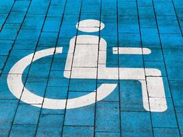 A parking area specifically reserved for disabled individuals is clearly marked with a blue background and a distinct accessibility symbol to ensure convenience and visibility photo