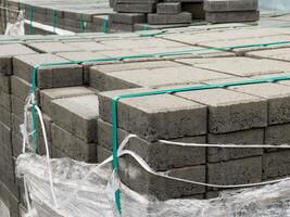 Cobblestones are neatly stacked and secured with straps, ready for a construction project. The site showcases organized materials essential for paving tasks photo
