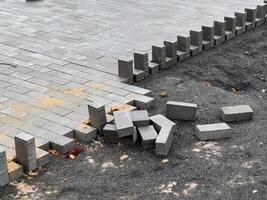 Workers are engaged in laying paving stones to create a durable pathway, with freshly placed stones visible alongside scattered bricks on the ground photo