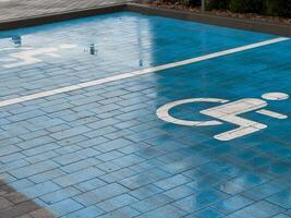 A blue pavement section is marked with a symbol indicating a designated parking spot for disabled individuals, highlighting accessibility in the area photo