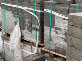 Cobblestones are organized in tall stacks, securely wrapped and prepared for delivery, showcasing their various textures and shades under bright daylight photo