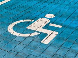 A designated parking spot for disabled individuals is clearly marked on the ground with a white symbol against a blue pavement surface, ensuring accessibility for all photo