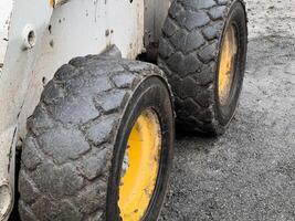 A bobcat loader featuring large, heavily treaded tires operates at a construction site, while an excavator stands ready for its next task photo
