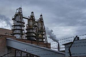 Heavy smoke rises from the tall smokestacks of an industrial facility amid a cloudy sky, reflecting the operations of an urban manufacturing site photo