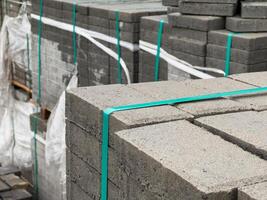 A large stack of cobblestones is neatly bundled and secured with green straps, ready for use in reinforcing sidewalks in an urban environment photo
