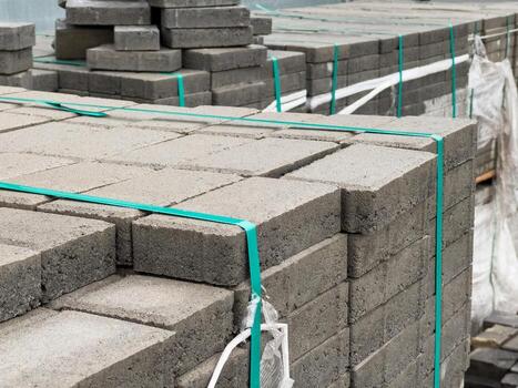 Stacks of cobblestone blocks are organized neatly at a construction site, ready for installation as part of sidewalk development in an urban area photo