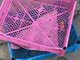 Colorful plastic crates are neatly stacked on a patterned pavement, indicating a vibrant market environment where goods are stored and displayed photo