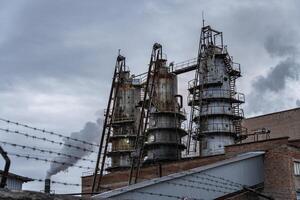 The tall structure features a brick facade and rusted metal supports, standing against a cloudy sky, indicative of an industrial environment in an urban setting photo