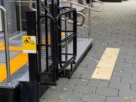 A ramp with a yellow sign that says handicap accessible. The ramp is made of metal and has a yellow and black stripe photo