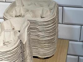 A collection of neatly stacked biodegradable packaging containers sits atop a wooden table, highlighting an eco-conscious approach in a contemporary kitchen space photo