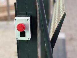 The striking red button, positioned at eye level, signals a commitment to safety, urging prompt action in emergencies at this bustling outdoor location photo