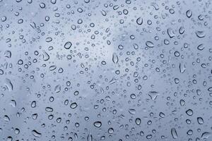 Delicate droplets gather on the glass surface, showcasing a gray and overcast sky. The atmosphere feels tranquil and introspective, evoking a sense of calmness photo