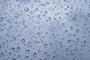 Delicate droplets accumulate on a window, blurring the view outside as gray clouds loom overhead during a quiet rainy afternoon photo