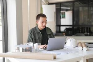Architecture in a green jacket sitting at a table with a laptop photo