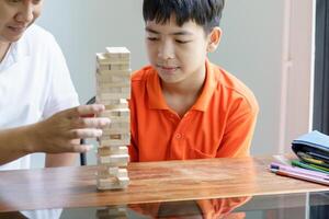 father and son playing wood blocks game Carefree kid playing wood blocks game building constructor from blocks with father at home photo
