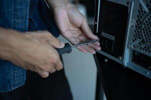 IT Engineer is holding a screwdriver to a computer photo