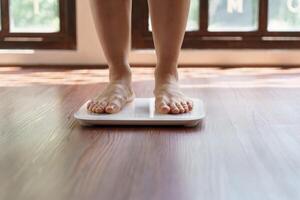 Fat diet and scale feet standing on electronic scales for weight control Measurement instrument in kilogram for a diet control. photo