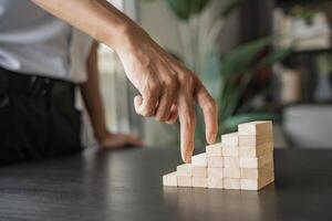 a person is pointing at a wooden block that is made up of cubes, business growth success photo