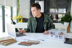 Architecture Man sitting at a table with a laptop and architectural plans photo