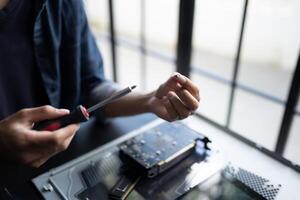 IT Engineer is holding a screwdriver and working on a computer photo